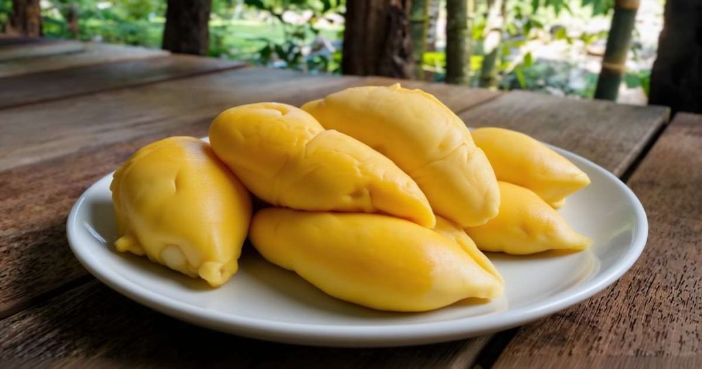 Durian fruit split open showing creamy yellow flesh pods on a market stall